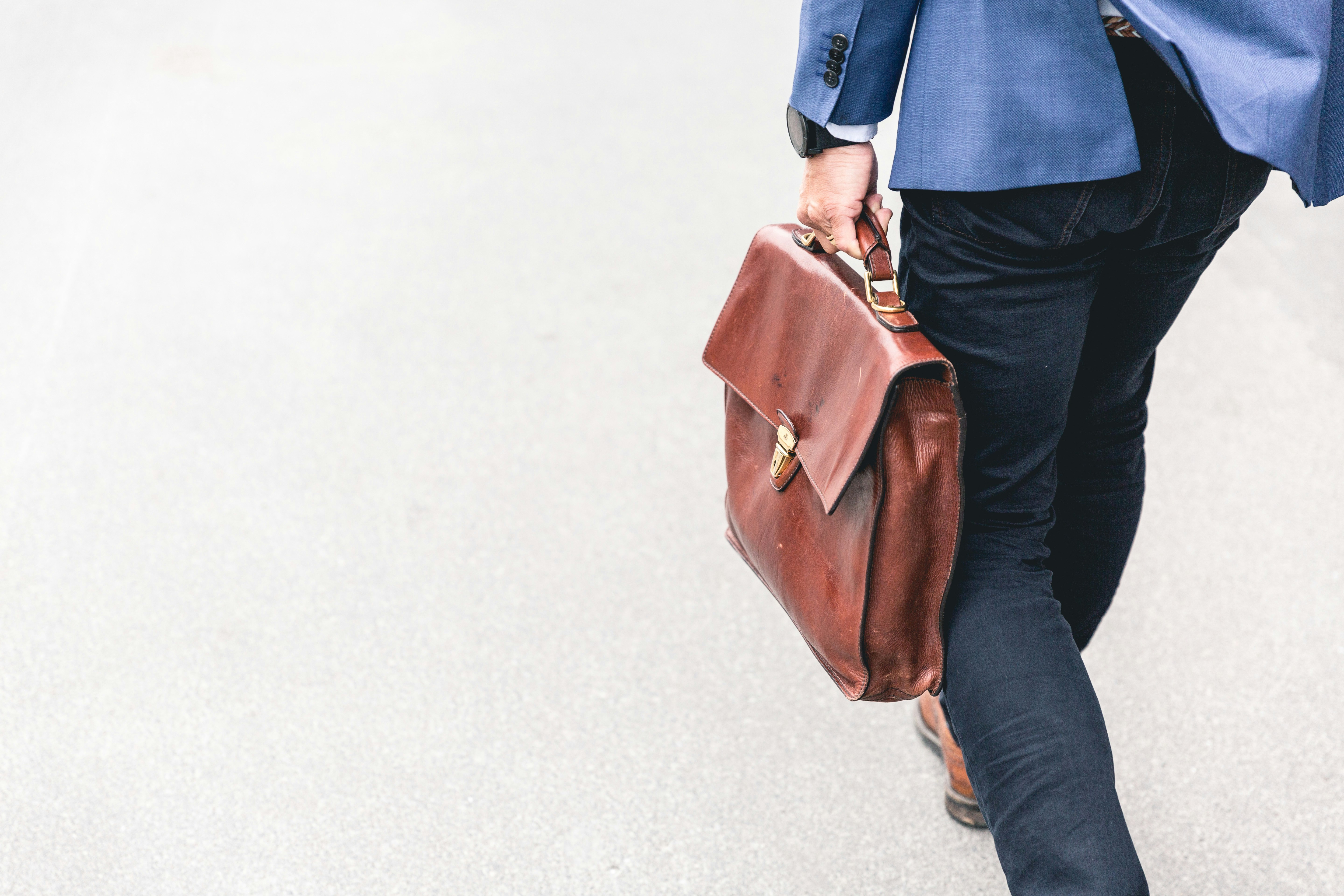 Business traveler walking with brown leather briefcase symbolizes Work permit in Switzerland