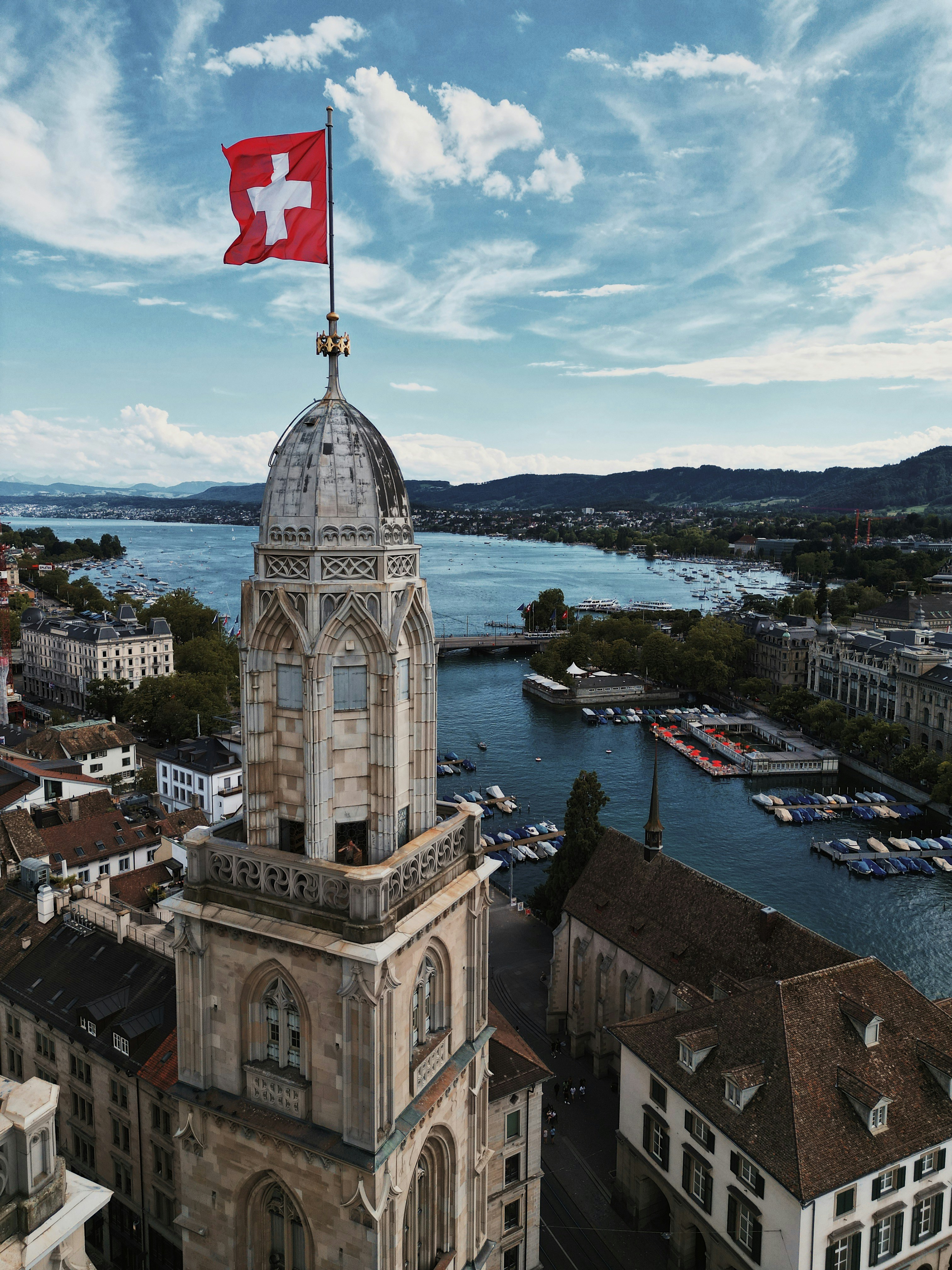 Aerial view of Zürich with the Grossmünster tower and Swiss flag overlooking Lake Zürich.
