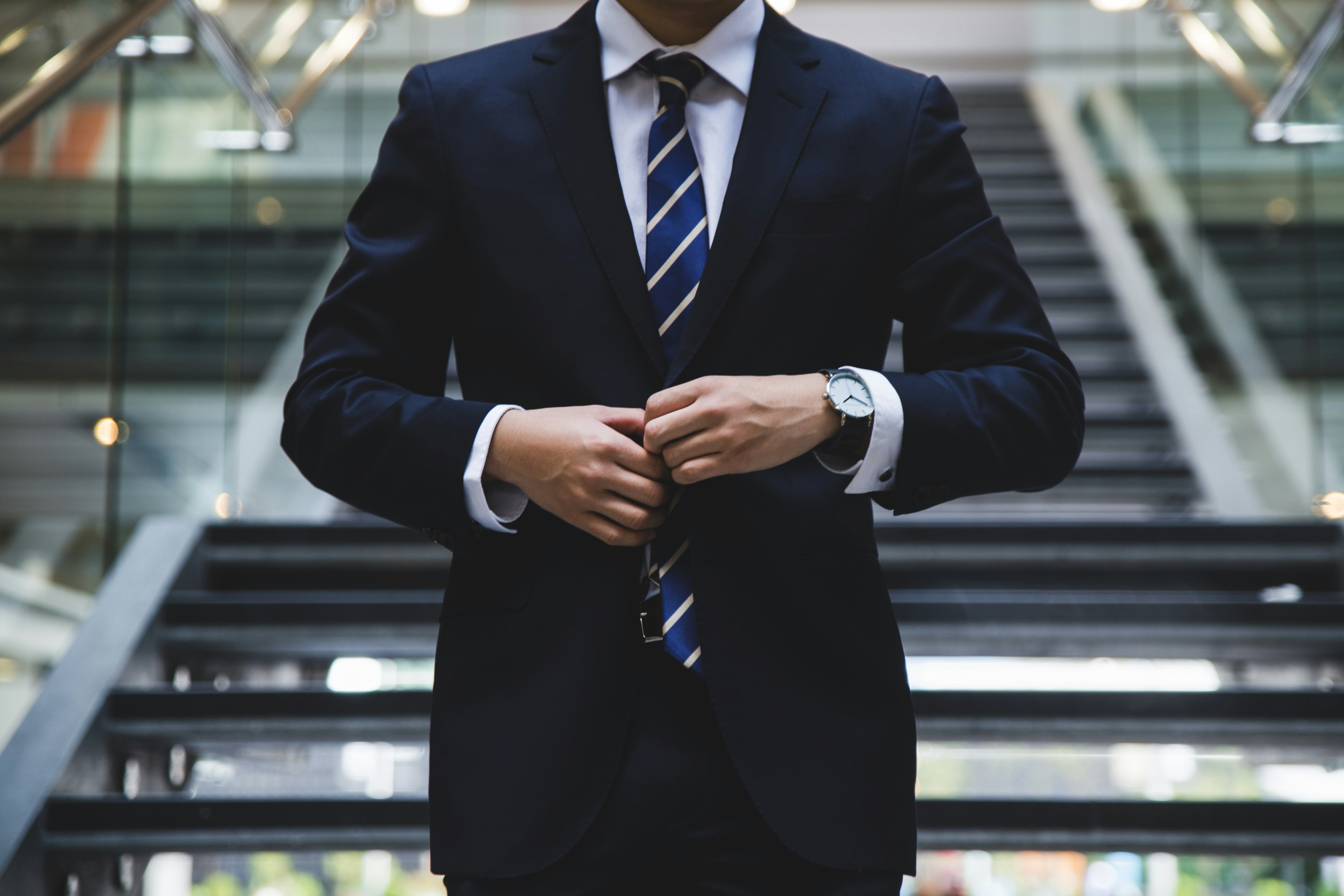 Business professional adjusting suit jacket in modern office environment symbolizes business/entrepreneur relocation